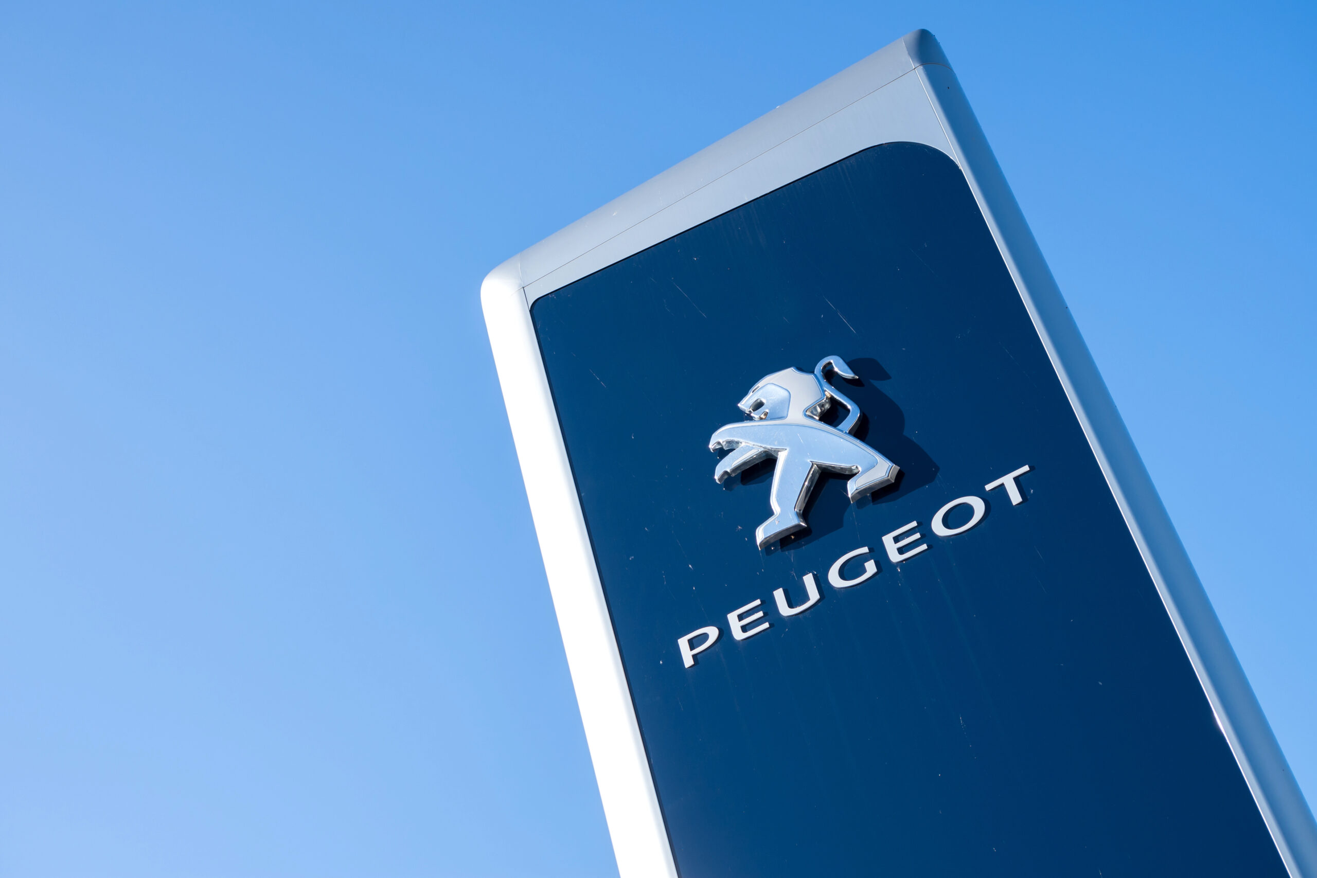 Panneau bleu Peugeot en contre-plongée avec un ciel bleu en fond