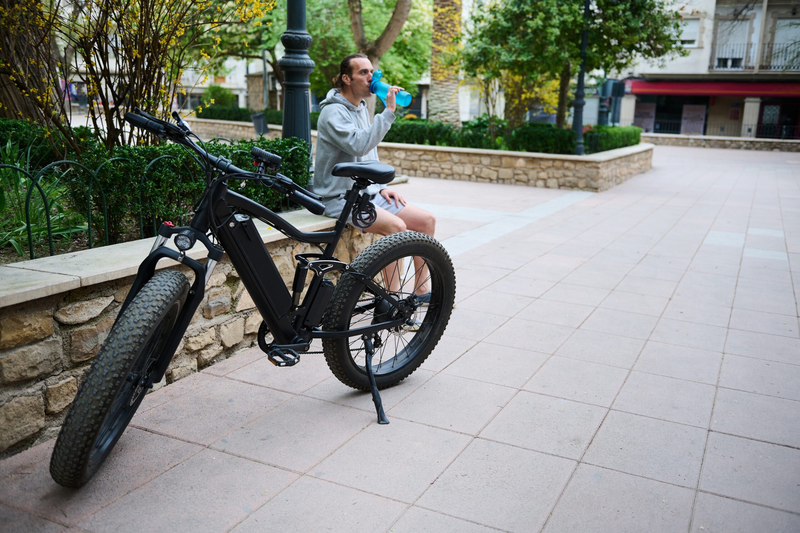 Vélo électrique sur une place avec un homme assis sur un muret derrière.